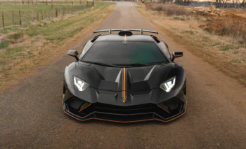 Чорний Lamborghini Aventador SVJ на порожній сільській дорозі