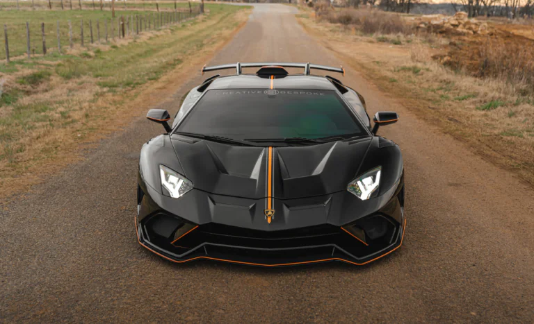 Черный Lamborghini Aventador SVJ на пустой проселочной дороге
