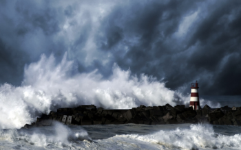 A red-and-white lighthouse under a heavy stormy sky