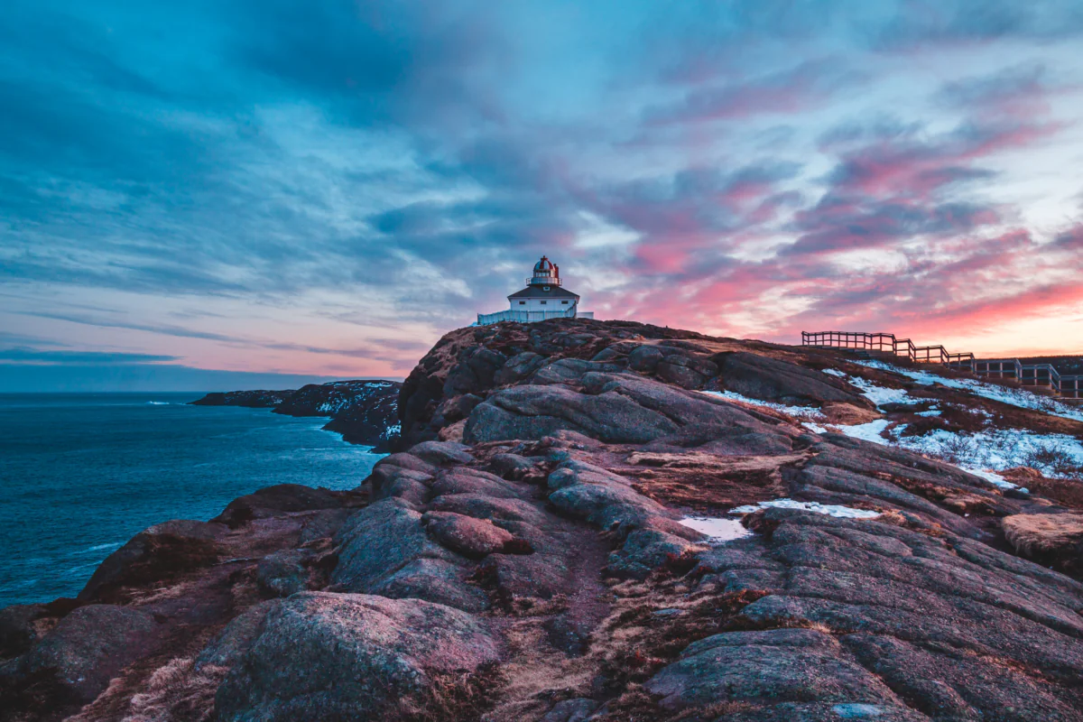 The lighthouse at Cape Spear in Canada against the backdrop of a pink sunset sky