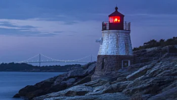Castle Hill Lighthouse at dusk, with the Cloud-Newport Bridge in the background, in the United States