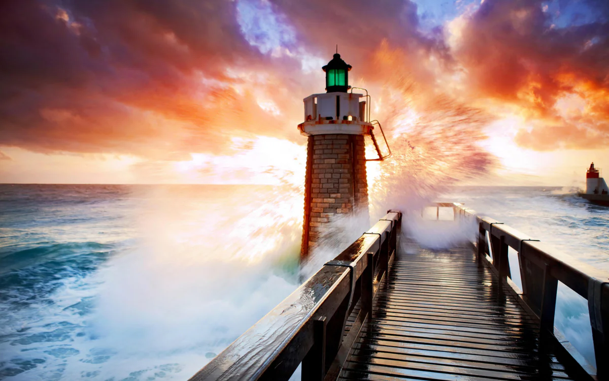 A stone lighthouse against the backdrop of a fiery sunset sky