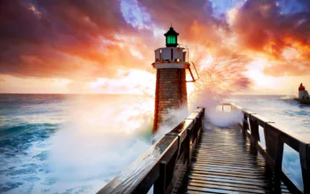 A stone lighthouse against the backdrop of a fiery sunset sky