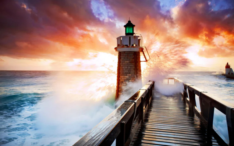 A stone lighthouse against the backdrop of a fiery sunset sky