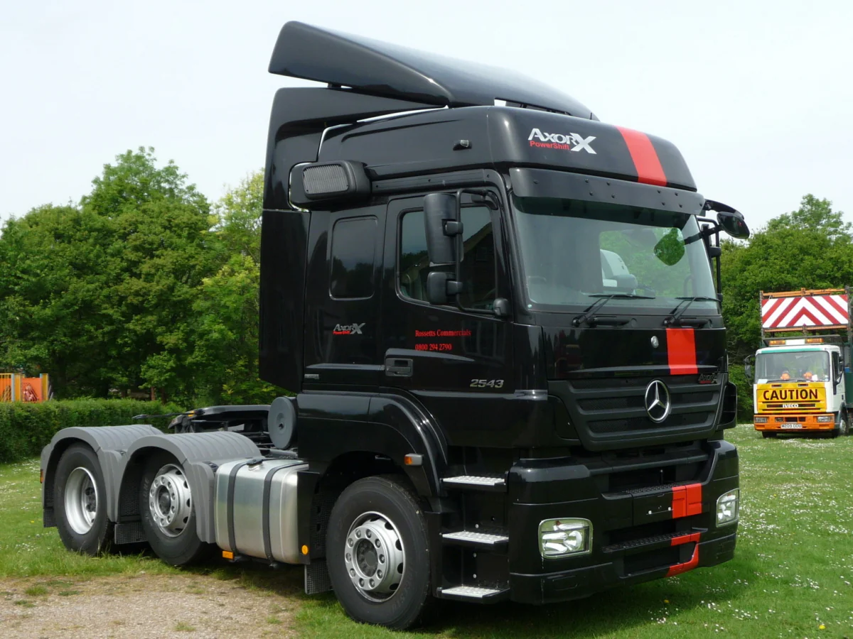 A black Mercedes-Benz Axor tractor-trailer on a green lawn