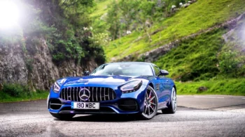 Синій Mercedes-AMG GT на звивистій гірській дорозі