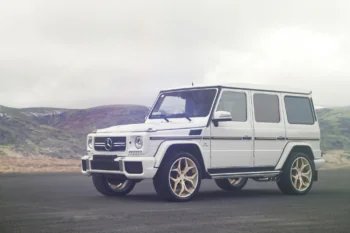 A white Mercedes-Benz G-Class against a backdrop of misty hills