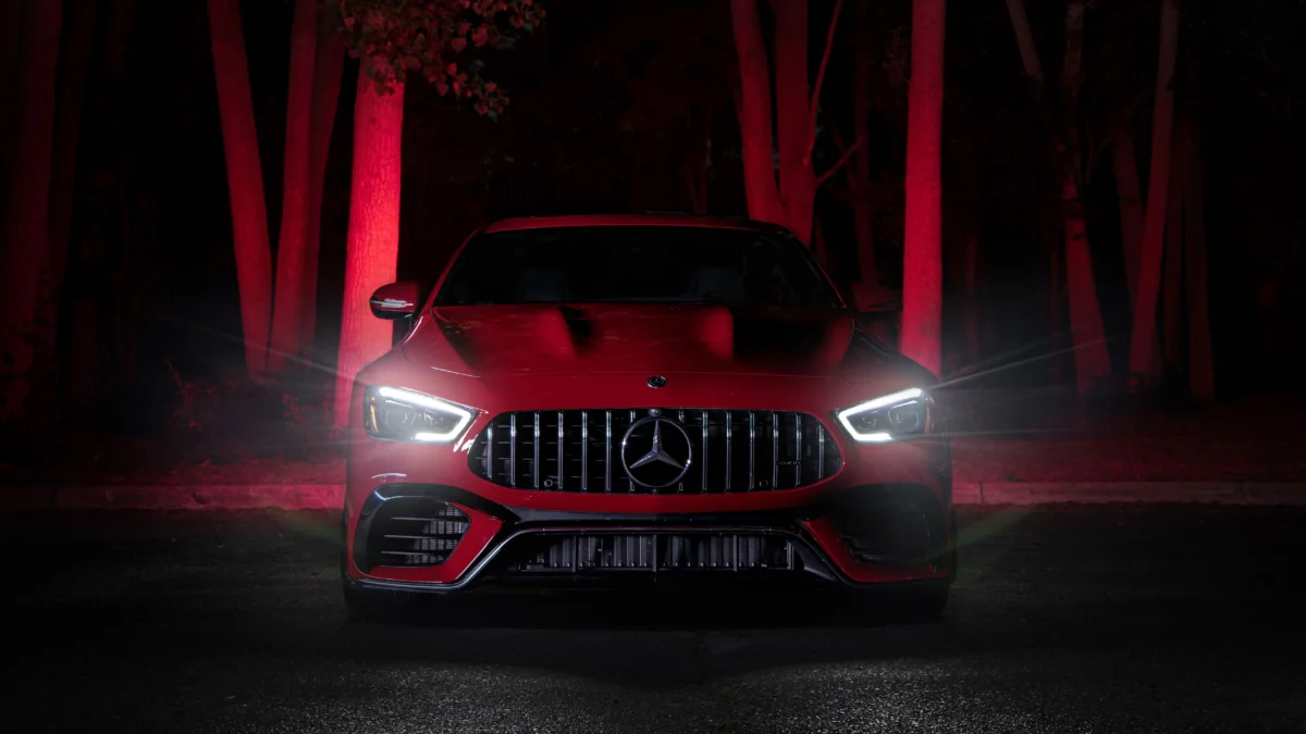 Червоний Mercedes-AMG GT у світлі нічних вогнів серед дерев