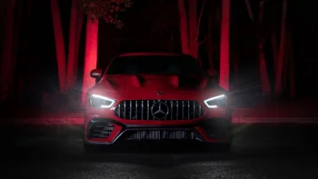 A red Mercedes-AMG GT illuminated by the night lights among the trees