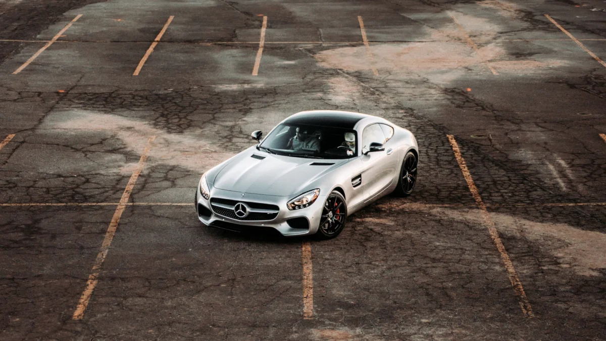 A silver Mercedes-Benz AMG GT in an empty paved parking lot