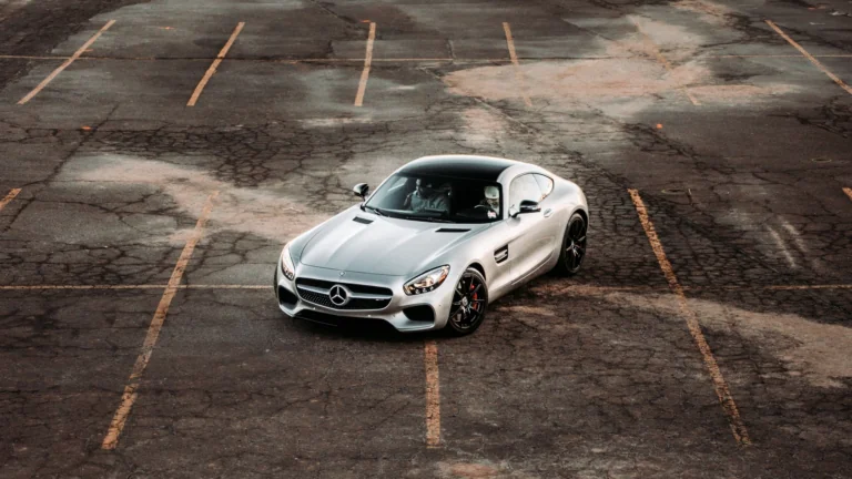 A silver Mercedes-Benz AMG GT in an empty paved parking lot