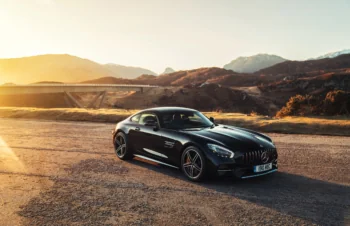 Чорний Mercedes-Benz AMG GT на тлі гірського пейзажу у променях заходу сонця