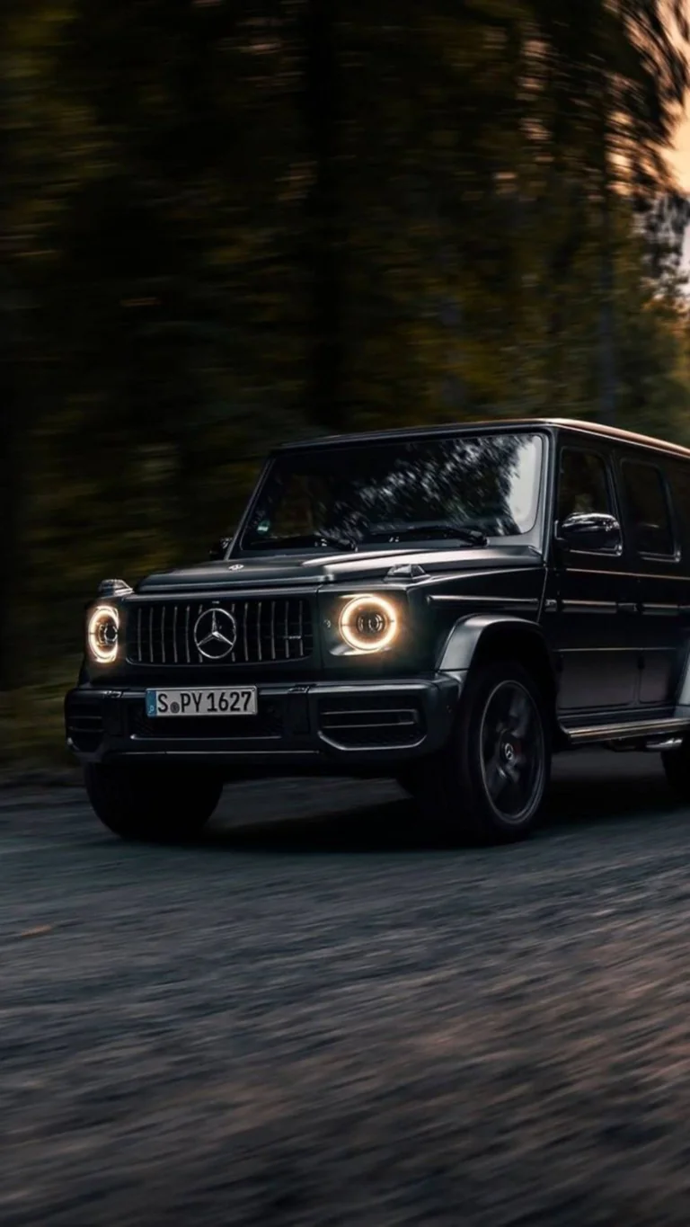 A black Mercedes-Benz G-Class speeding down a forest road
