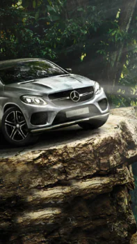 A silver Mercedes-Benz GLE Coupe on the edge of a cliff in a dense forest