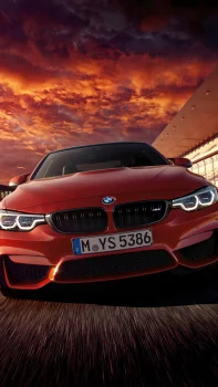 Червоний BMW M4 на тлі палаючого неба під час заходу сонця