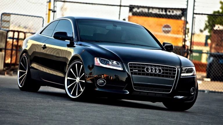 Черная Audi A5 купе на фоне индустриального пейзажа