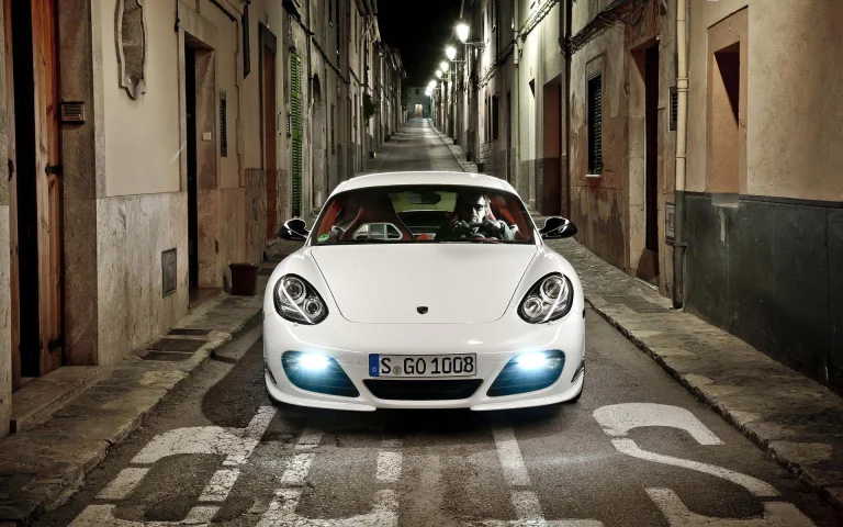 Білий Porsche Cayman у вузькому провулку нічного міста