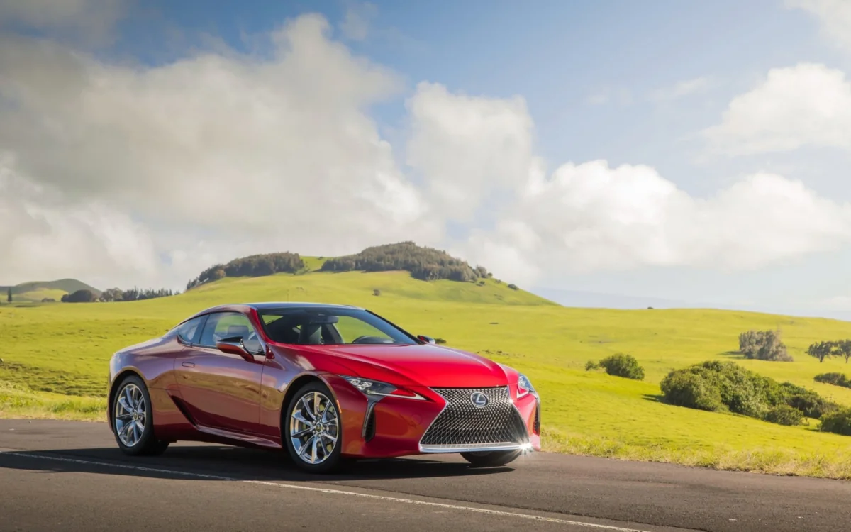 Красный Lexus LC на фоне зеленых холмов