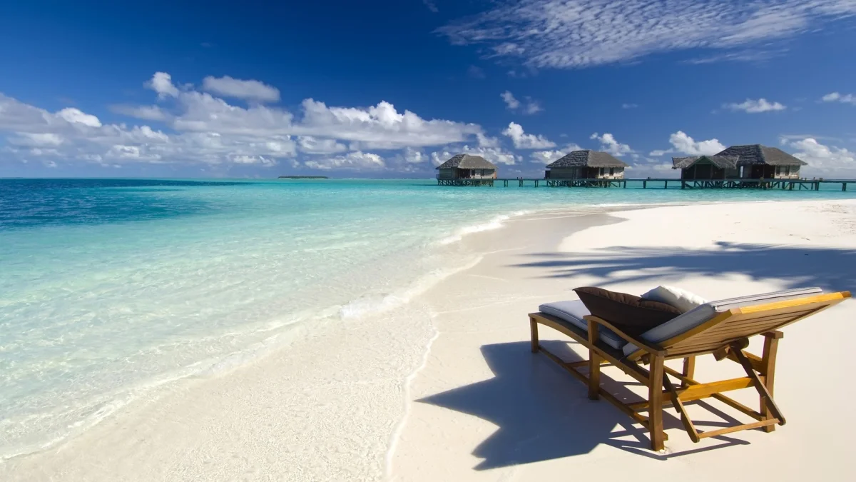 A lounge chair on the snow-white sand of a tropical lagoon