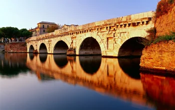 a golden sunset over the ancient tiberius bridge in rimini, attractions, bridges, evening, evenings, twilight, dus, houses, buildings, italy, reflections, rivers, canals, streams, sunsets, sunset, architecture, world