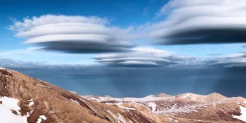Lenticular clouds over snow-capped mountain peaks