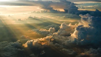 Golden rays of sunlight breaking through thick layers of cumulus clouds