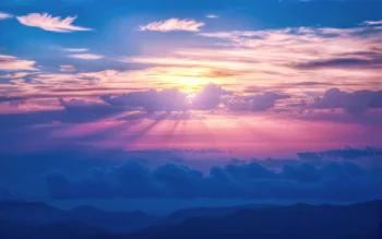 The pink rays of the setting sun over the mountainous horizon