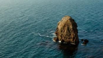 A solitary rock in the middle of the calm ocean waters