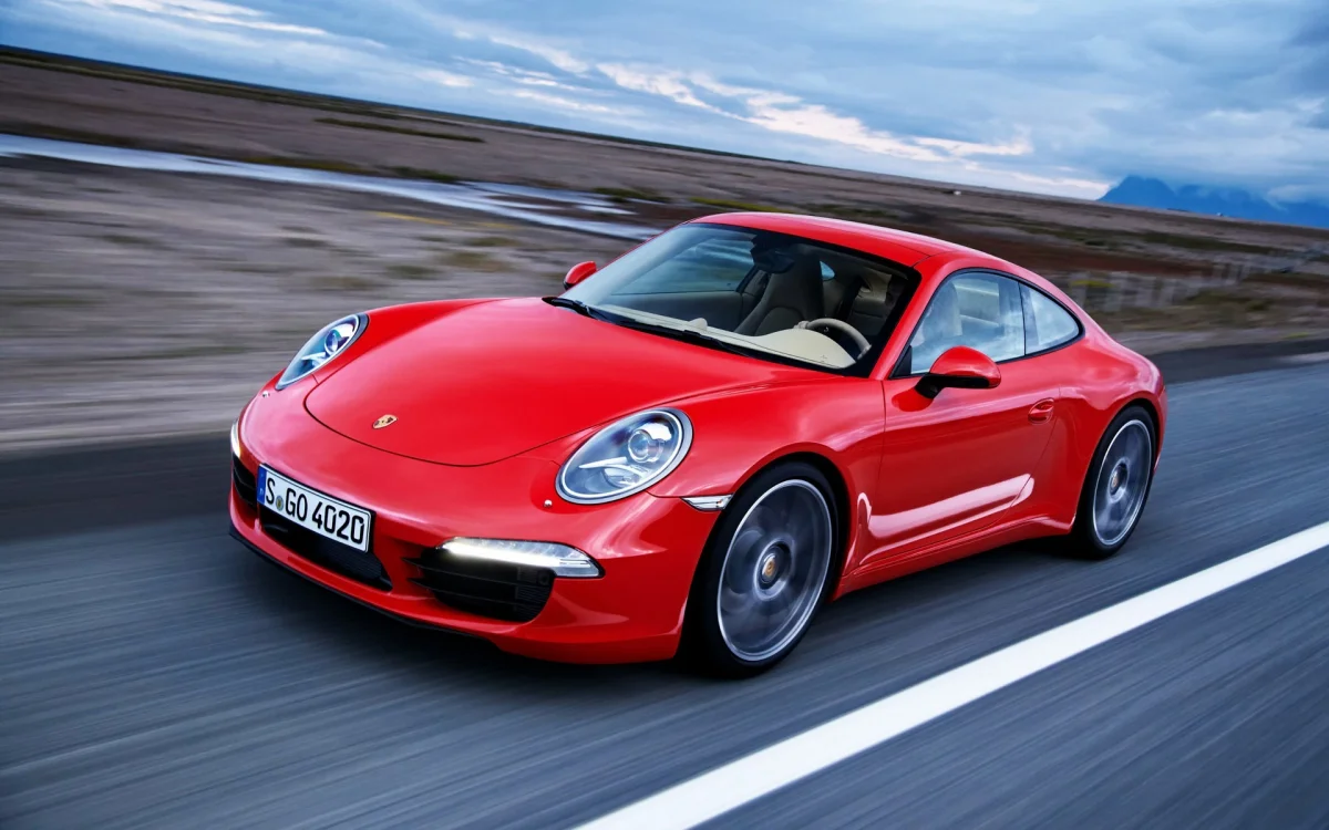A red Porsche 911 is speeding down a deserted road