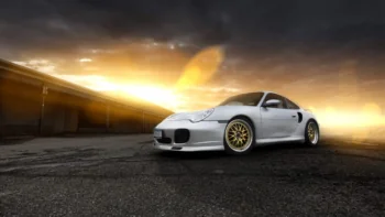 A silver Porsche 911 Turbo against the backdrop of a sunset sky