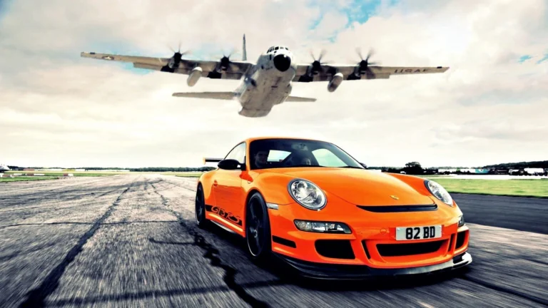 Оранжевый Porsche 911 GT3 RS на взлетной полосе под пролетающим самолетом