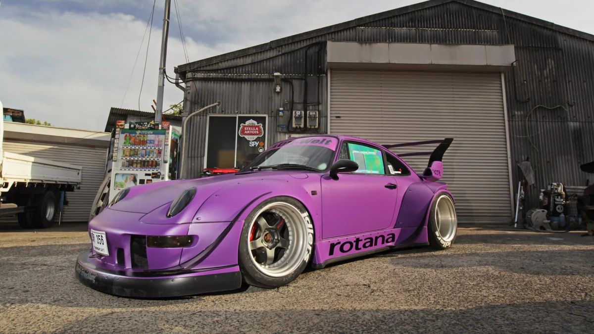 Фиолетовый Porsche 911 RWB Rotana у промышленного ангара