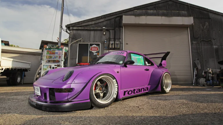 Фиолетовый Porsche 911 RWB Rotana у промышленного ангара