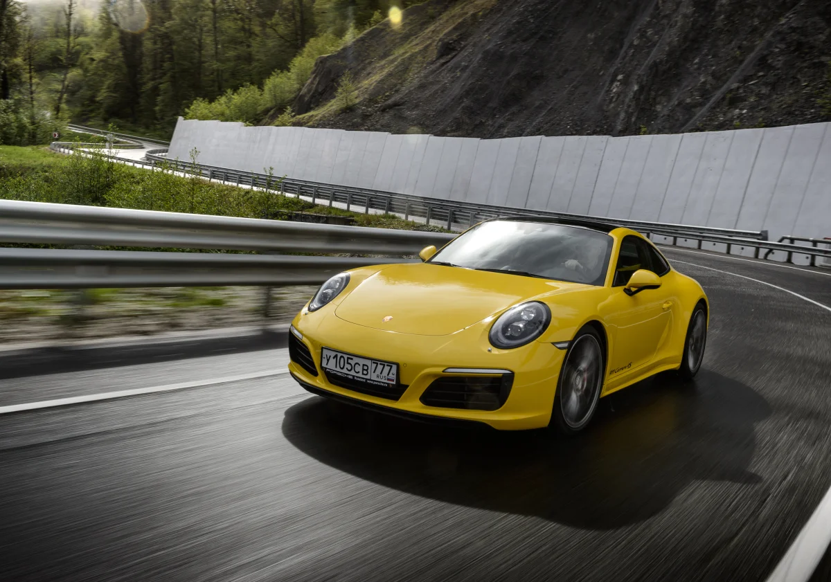 Желтый Porsche 911 Carrera 4S на извилистой горной дороге