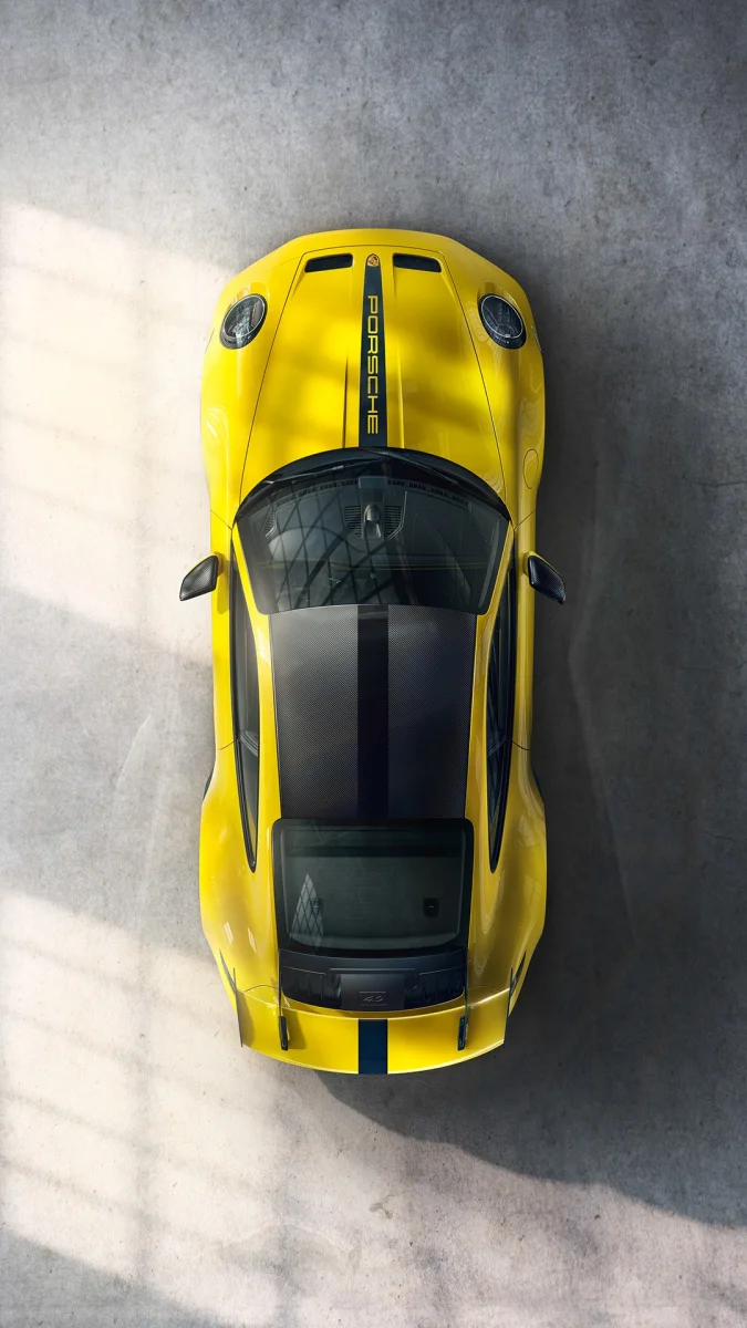 A bright yellow Porsche 911 GT2 RS bathed in light on a concrete floor