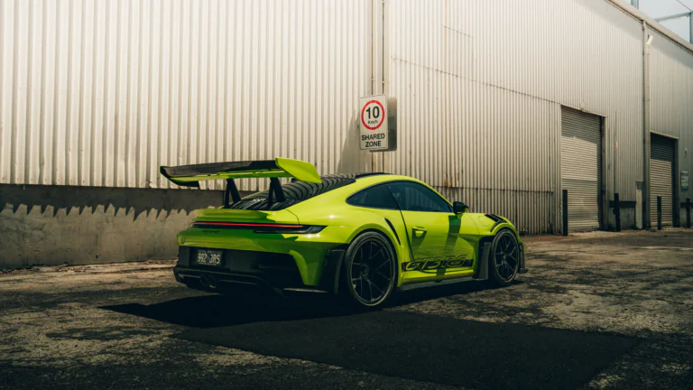 Яскраво-зелений Porsche 911 GT3 RS на тлі промислової стіни