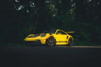 A bright yellow Porsche 911 GT3 RS on a forest road