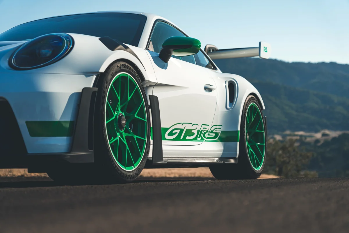 Білосніжний Porsche 911 GT3 RS із яскраво-зеленими акцентами на тлі пагорбів у променях сонця