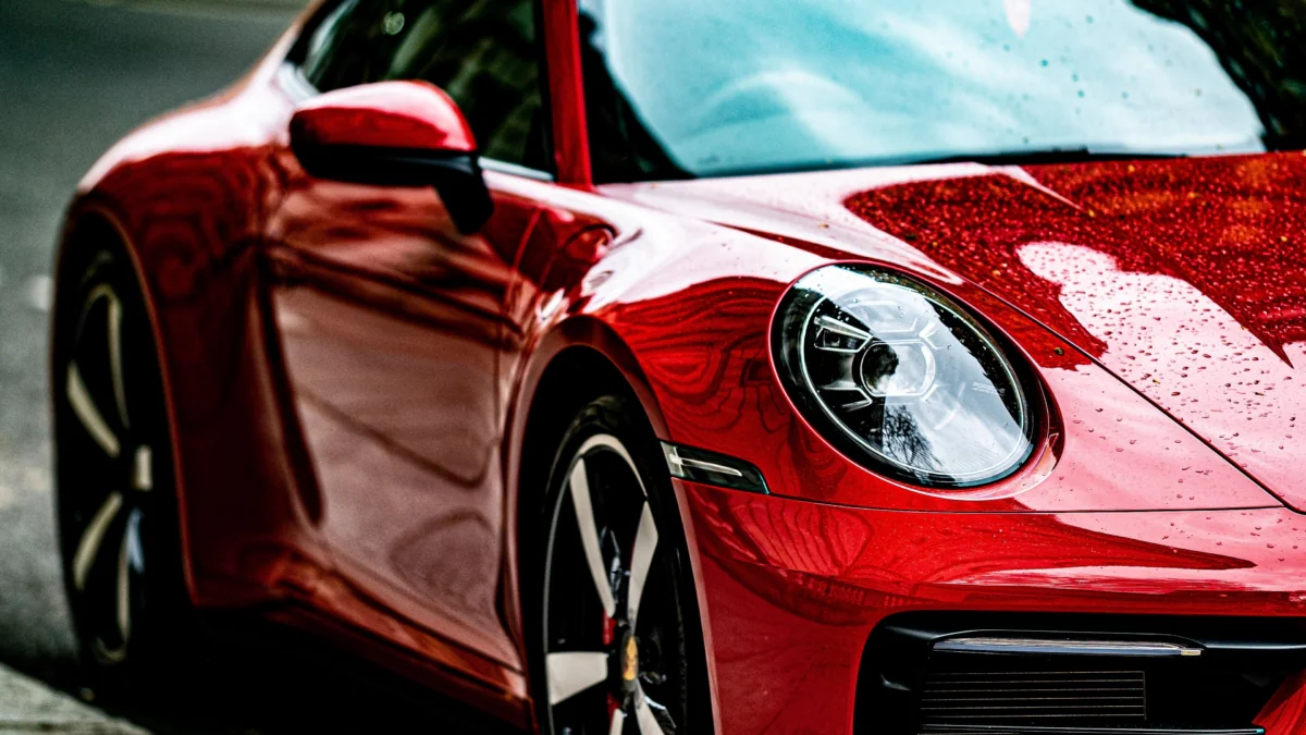 A red Porsche 911 with raindrops on the hood