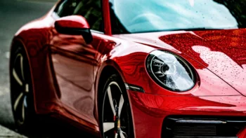 A red Porsche 911 with raindrops on the hood