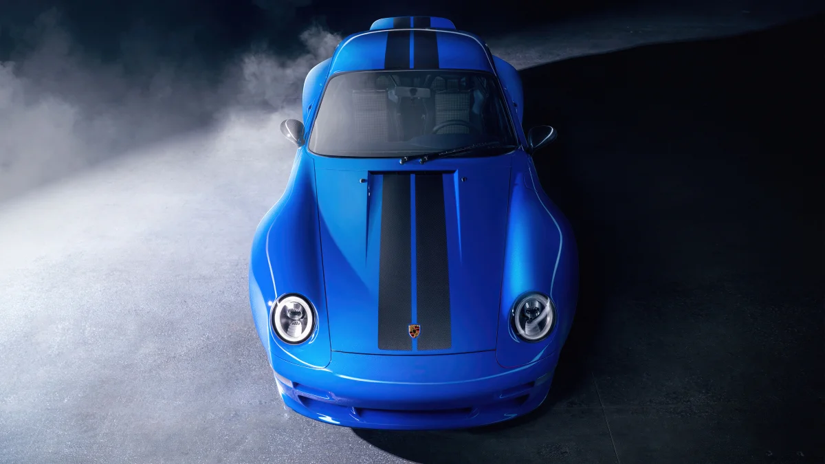 A blue Porsche 911 amid clouds of smoke under spotlights