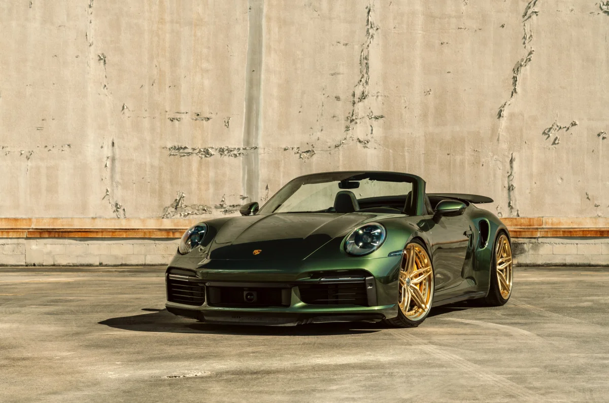 Изумрудный Porsche 911 Turbo S Cabriolet на фоне бетонной стены