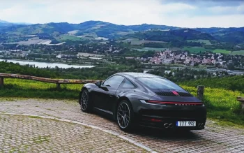 A black Porsche 911 against the backdrop of a hilly Italian landscape