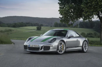 A silver Porsche 911 R against a backdrop of green hills