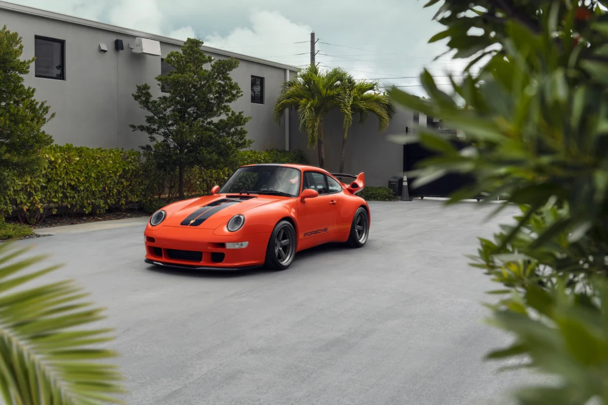 Яскраво-помаранчевий Porsche 911 на парковці біля будинку