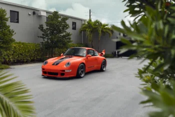 Яскраво-помаранчевий Porsche 911 на парковці біля будинку