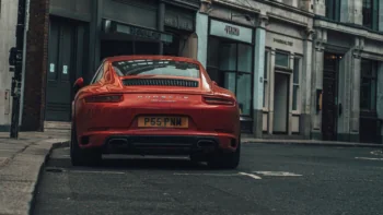 A red Porsche 911 Carrera on an empty London street