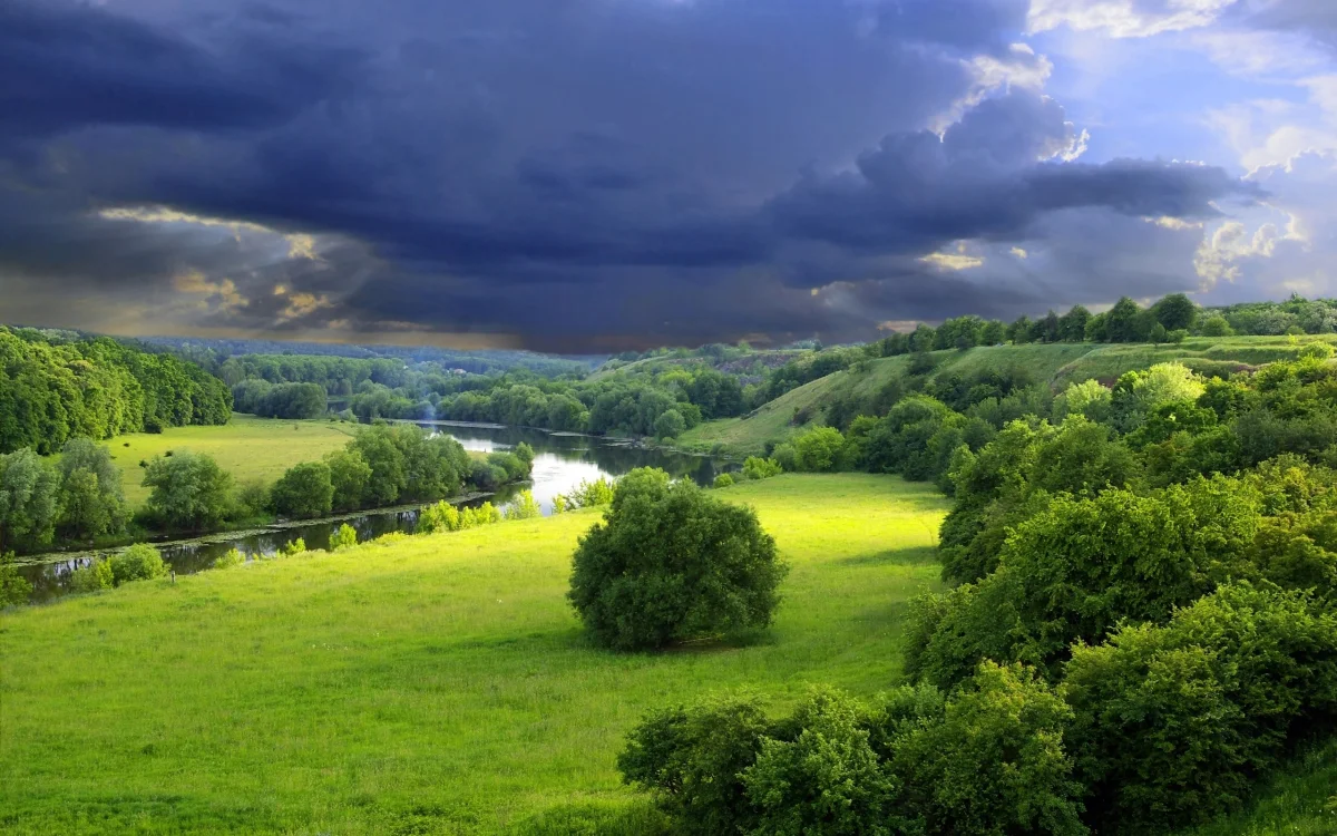 Green meadows and a winding river beneath a stormy sky