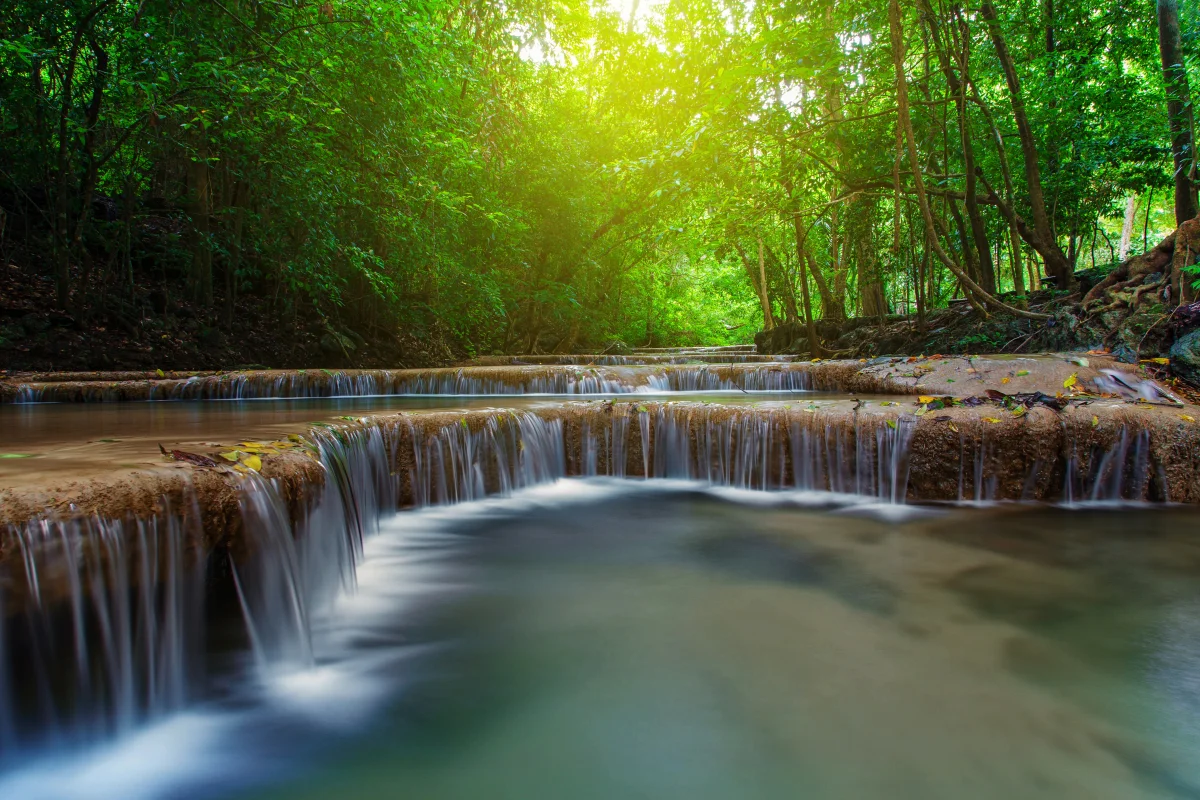 Sunbeams in the tropical forest above the cascades of Erawan Falls
