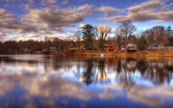 A peaceful lakeshore with houses under a cloudy sky